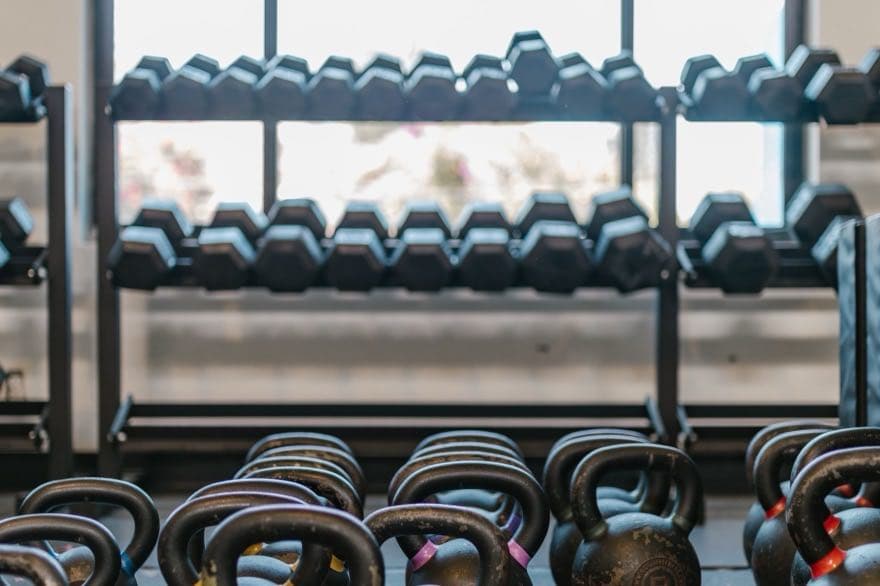 Giá tạ tay xếp thành hai hàng trước ô cửa sổ, phía dưới là dãy tạ ấm